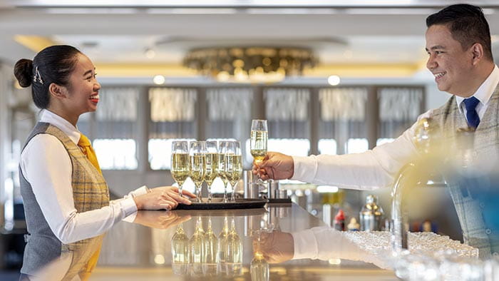 Staff serving sparkling wine in the Britannia Lounge on Spirit of Adventure